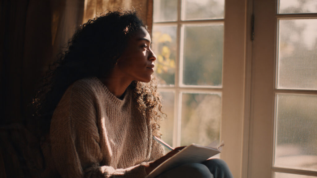 Black woman reflecting quietly in morning light as she begins her intentional living journey.