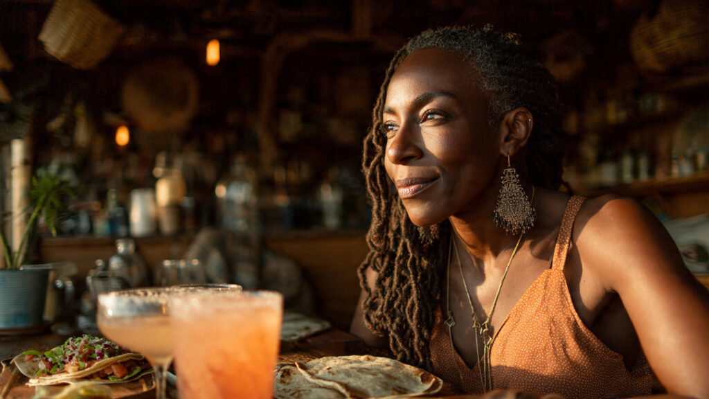 Black woman enjoying taco night with a cocktail, exploring cocktails that go with tacos during a relaxed happy hour.